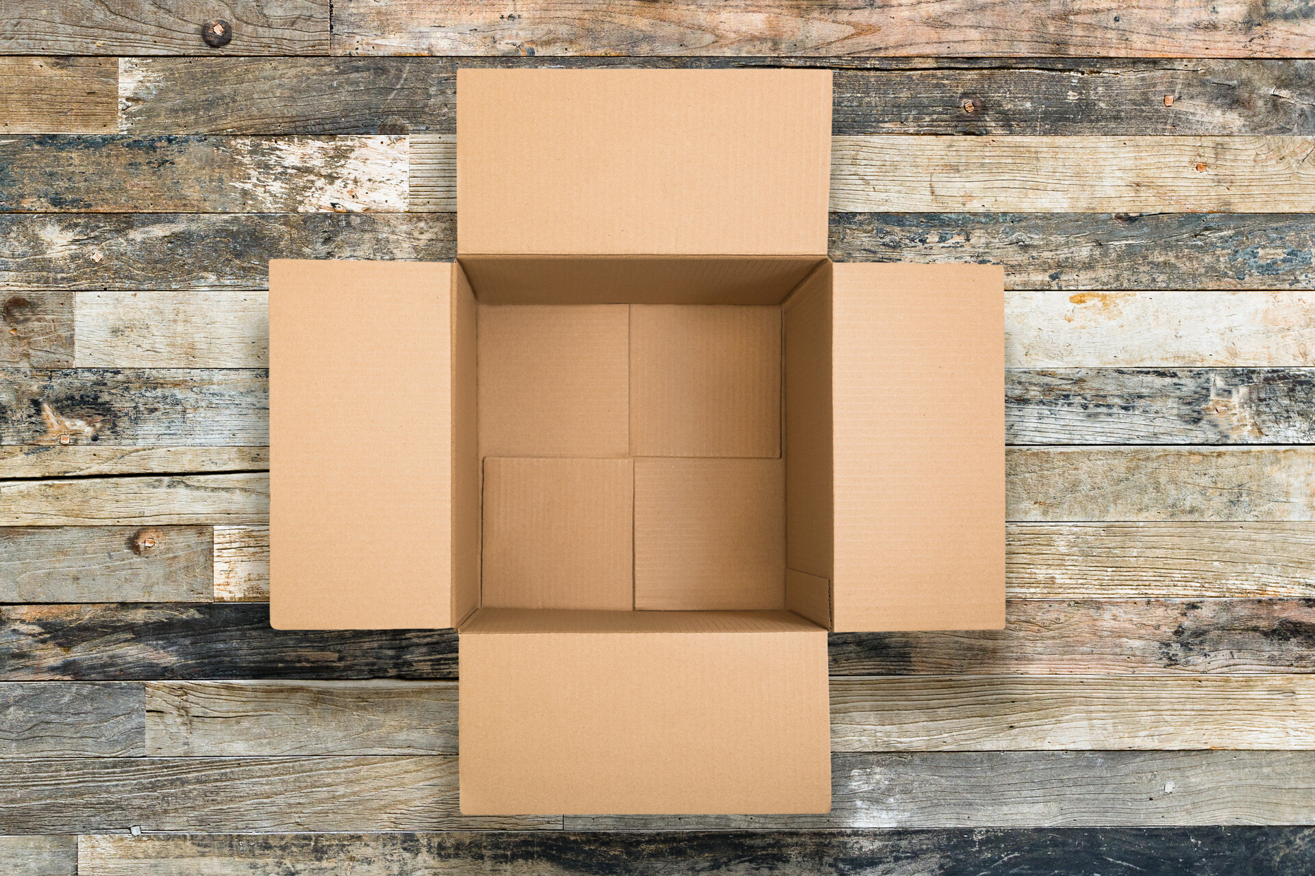 Empty cardboard box on a rustic wooden surface, viewed from above.