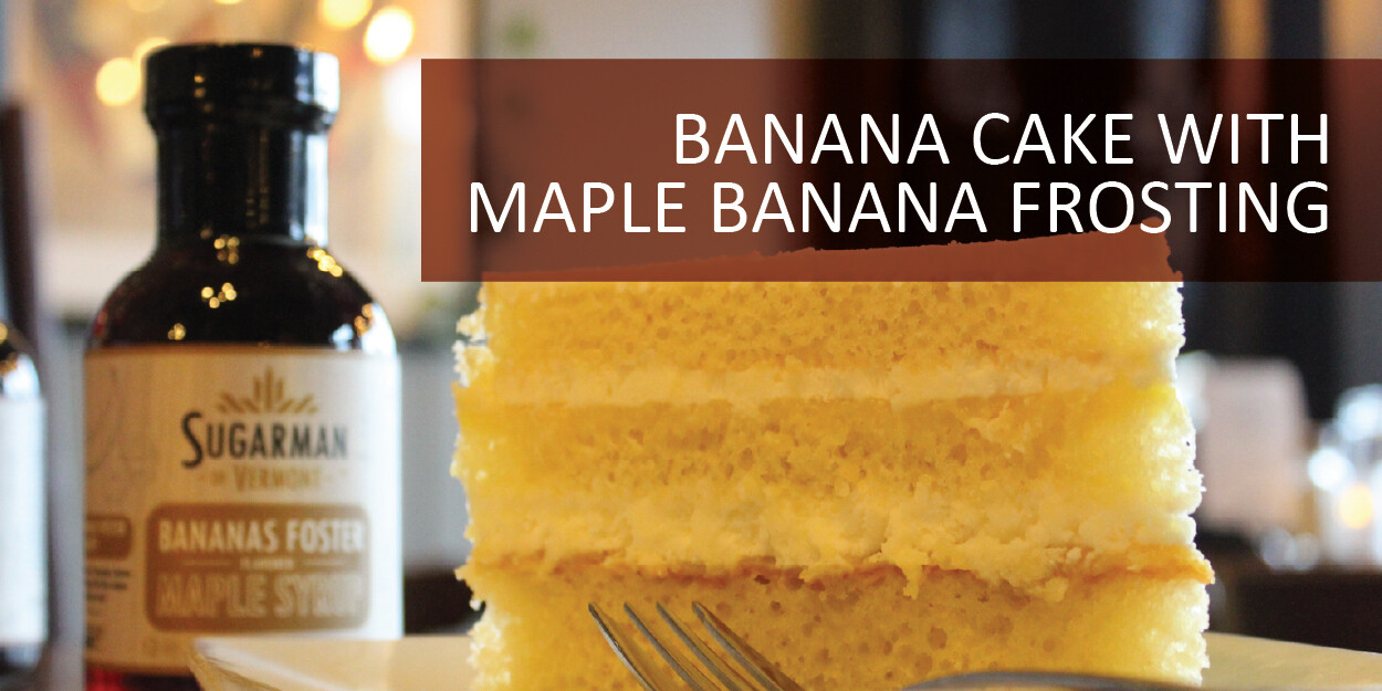Layers of banana cake with maple banana frosting and syrup in the background.