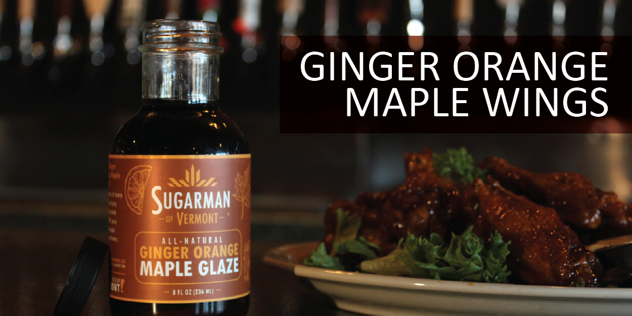 Bottle of ginger orange maple glaze with chicken wings on a plate.