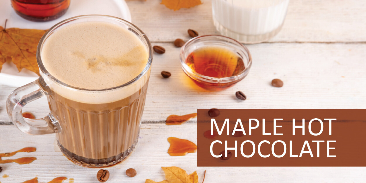 A glass of maple hot chocolate surrounded by coffee beans and syrup.