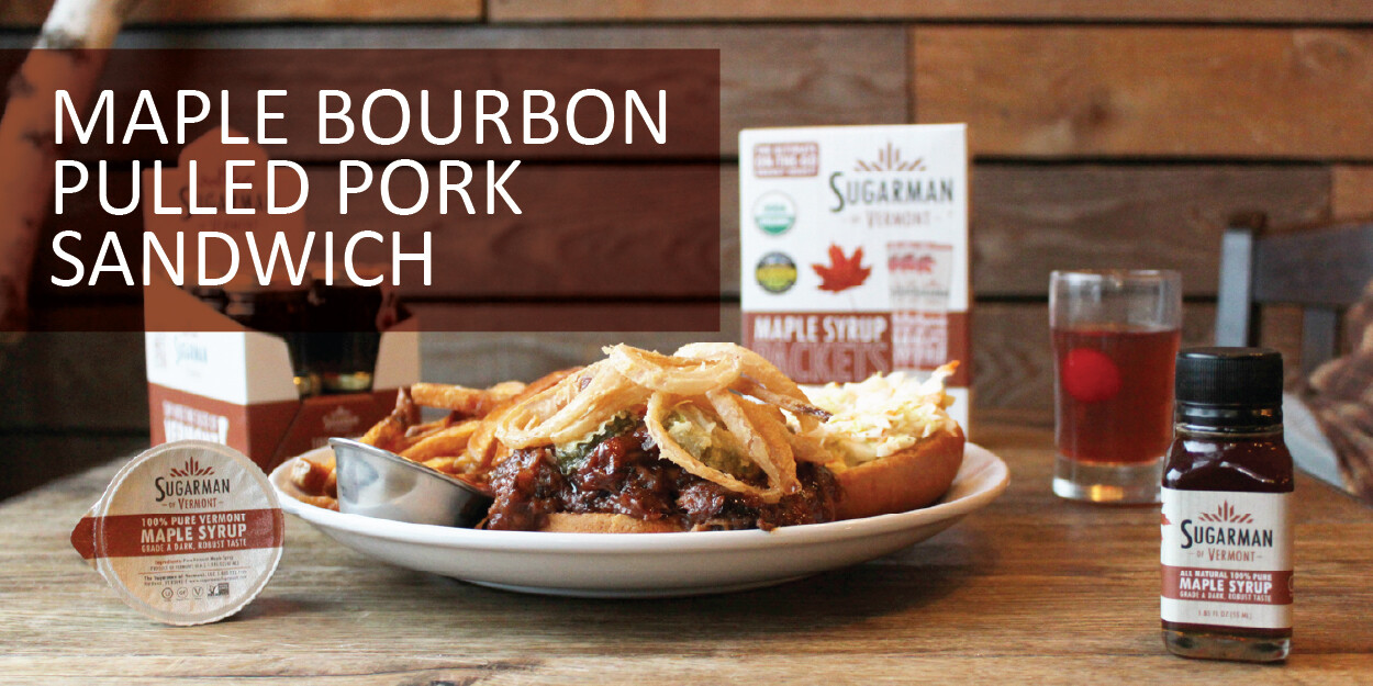 Maple bourbon pulled pork sandwich with fries, syrup, and a drink on a wooden table.